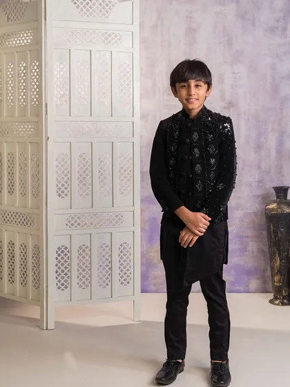 This is a sophisticated Indo-western outfit I created for an older boy. It features a heavily embellished black velvet jacket worn over an asymmetrical black kurta and trousers, ideal for a formal wedding reception.