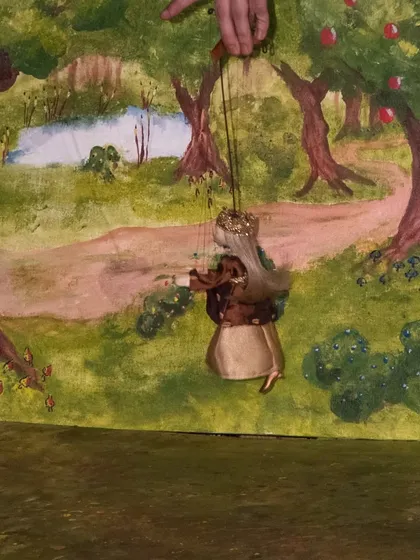 A princess marionette plays the violin against a beautiful, hand-painted forest scene in the Hungarian folktale performance.