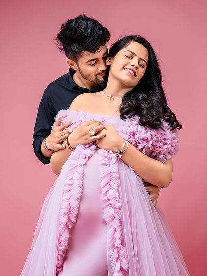 An intimate couple's portrait against a pink backdrop. The Clara gown is the perfect choice for a romantic and coordinated shoot.