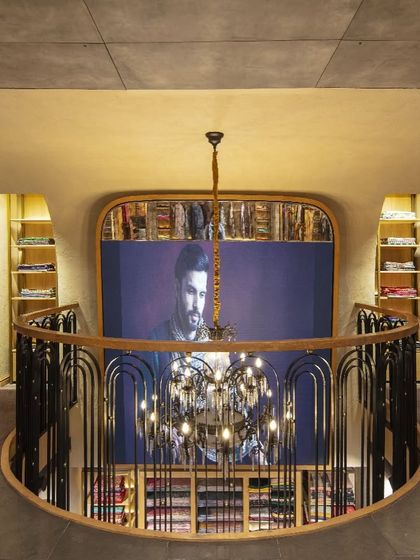 The mezzanine level at Ahujasons offers a dramatic overlook of the ground floor. This vantage point highlights the store's spatial choreography, with the custom railing and chandelier acting as key design elements that blend traditional and modern aesthetics.