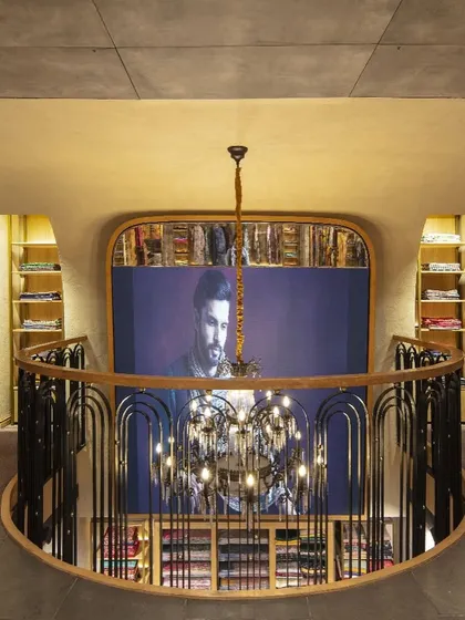 The mezzanine level at Ahujasons offers a dramatic overlook of the ground floor. This vantage point highlights the store's spatial choreography, with the custom railing and chandelier acting as key design elements that blend traditional and modern aesthetics.