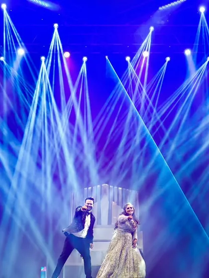 The first dance, illuminated by dramatic stage lighting. We have the expertise to capture high-energy reception and Sangeet moments, ensuring your party photos are as dynamic and exciting as the event itself.