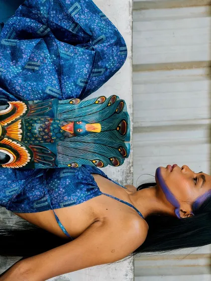 A conceptual shot from the "Nazaar" editorial series. The image combines a traditional mask with modern styling, set against a natural, rustic backdrop.