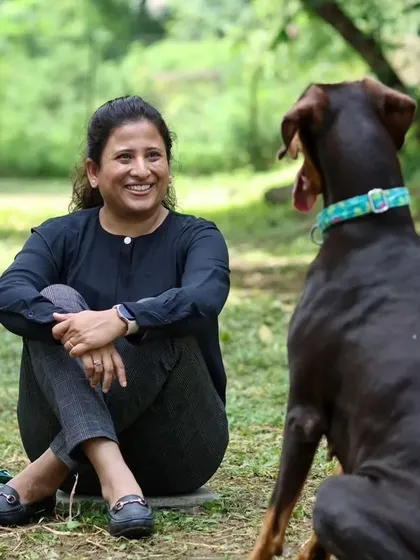 A trainer shares a smile with a Doberman. We celebrate the experts whose passion and patience enrich the lives of so many pets and their families.