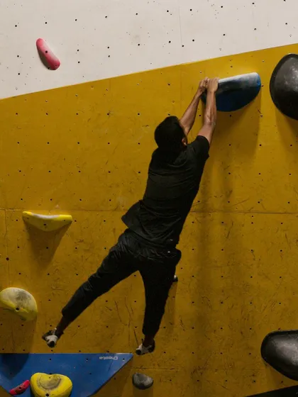 A climber hangs on, showing the grip strength required after a dynamic move. Our workshops help you build the power needed to stick these challenging holds.