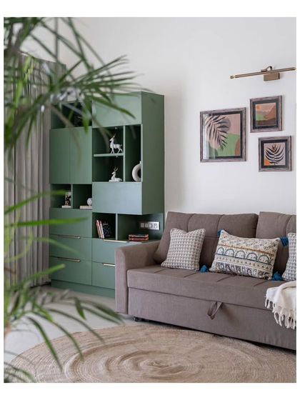 Another view of the study's green storage unit and sofa-bed, creating a cozy and functional corner. A round jute rug anchors the space, adding to the room's warm, earthy feel.