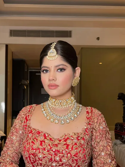 A close-up of a bride in a classic red lehenga. The styling focuses on the beautiful diamond jewelry and the soft, glamorous makeup.