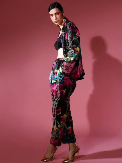 A side profile of a model in a printed co-ord set, worn as a jacket over a simple black bralette. This styling choice gives the look a relaxed yet chic edge.