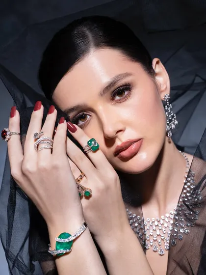 A full view of the dramatic styling for a fine jewelry campaign. The combination of multiple rings, a statement bracelet, and earrings against a sheer veil creates a look of opulent mystery.