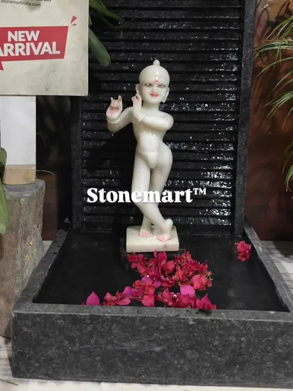 This 3-foot granite waterfall features a beautiful white marble Kanha Ji (Krishna) sculpture. It's a perfect fountain for bringing a spiritual and positive ambiance to a home, with the gentle sound of water in the background.