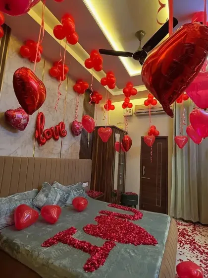 To make your partner feel incredibly special, I can transform your bedroom into a romantic haven. This decoration features hundreds of red balloons, heart-shaped foil balloons, and a bed covered in rose petals spelling out 'I love you'.