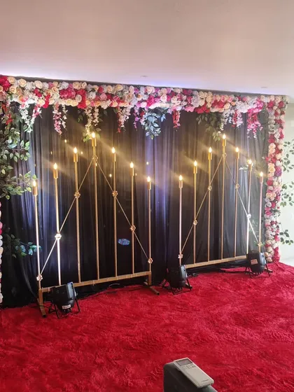 A duplicate image of the dramatic backdrop for a Mehndi or Sangeet night, with dark curtains and candelabras.