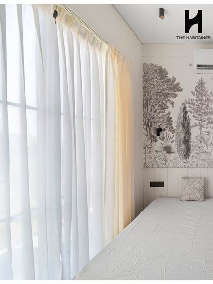 The master bedroom in the Denkanikotta project is bright and serene. It features a stunning botanical accent wall behind the bed and floor-to-ceiling windows draped in sheer curtains.
