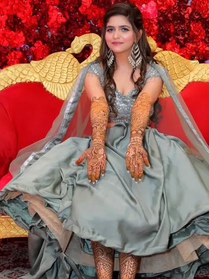 The bride showing off her beautiful, full-hand Mehendi design, with her makeup looking flawless.