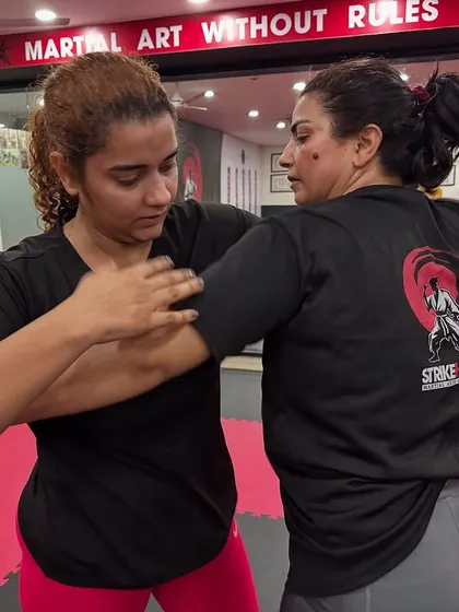 An instructor provides one-on-one guidance on blocking and arm control during a Brazilian Jiu-Jitsu class. We ensure every student receives personal attention to refine their technique.