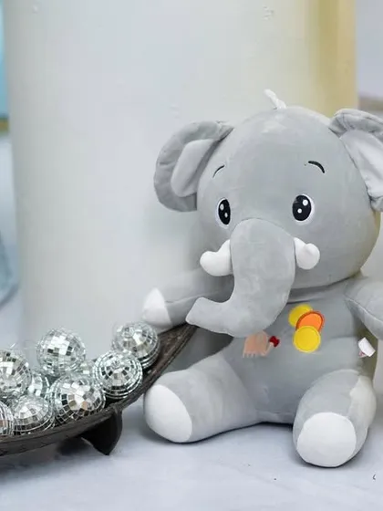 A plush baby elephant toy sits next to a boat of mini disco balls, a fun and quirky detail from a child's birthday party.