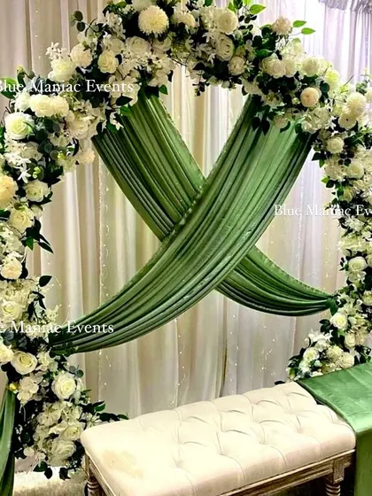 A beautiful Nikkah or engagement setup featuring a circular arch with white flowers and lush green draping. The design is clean, elegant, and perfectly suited for intimate ceremonies, providing a serene backdrop for the couple.