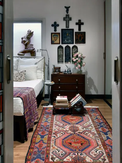 A view into the bedroom through stained glass doors inspired by Frank Lloyd Wright. The room features a collection of Christian icons and crucifixes, reflecting a personal appreciation for sacred art from around the world.