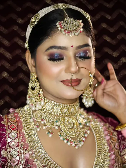 A bride adorned in a deep magenta lehenga with sparkling blue eyeshadow. This look demonstrates how to use bold colors in a sophisticated way, a key skill for modern bridal artists.