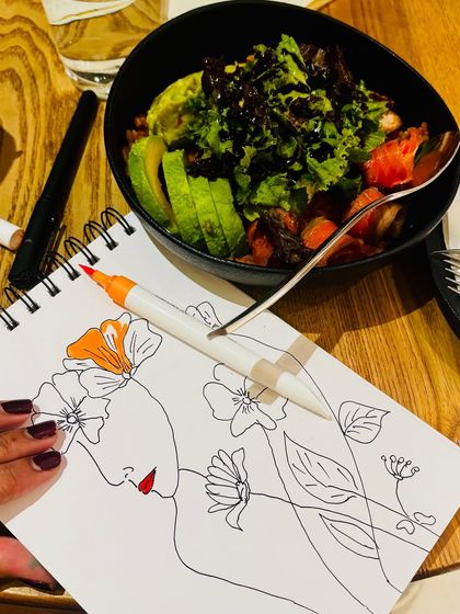 A close-up of my sketchbook and a healthy salad, blending my passions for art and good food.