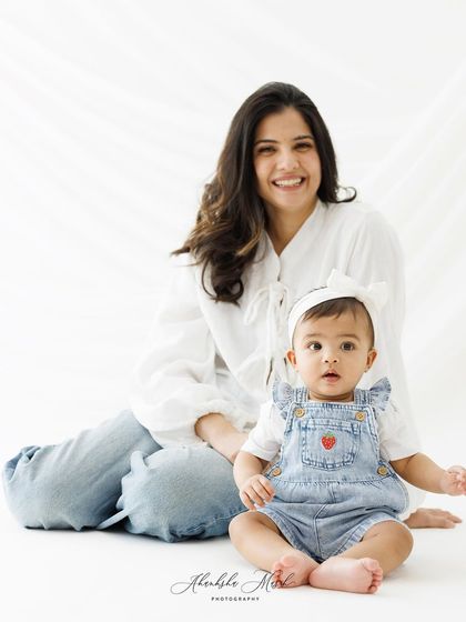 A beautiful seated portrait of this mother and child. The baby's curious expression and the mother's gentle smile make for a heartwarming image.