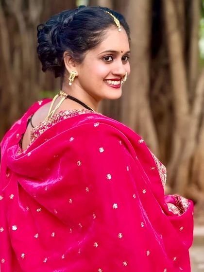 A radiant smile from a client looking over her shoulder. This highlights the beautiful hairstyle and jewelry that completes the traditional Maharashtrian look.