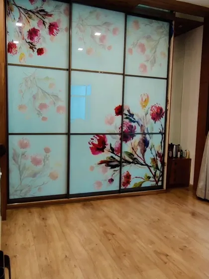This is a custom-designed sliding wardrobe with floral-printed glass panels. It acts as a piece of art in the bedroom, showing how functional storage can also be a beautiful focal point.