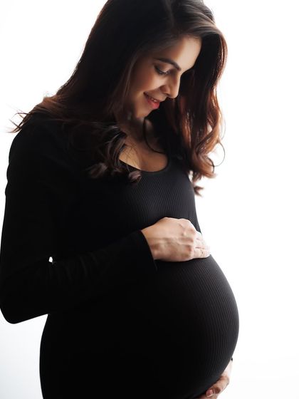 A classic maternity pose, beautifully backlit to create a soft glow. This portrait in a simple black dress is all about celebrating the beautiful shape of pregnancy.