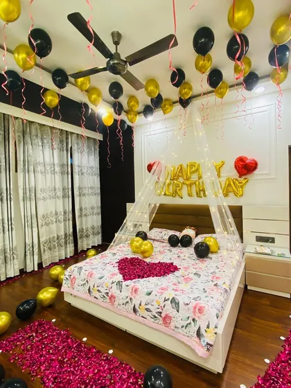 Another angle of the romantic birthday room. This view shows the detail of the fairy light canopy and the arrangement of balloons and rose petals from a different perspective.