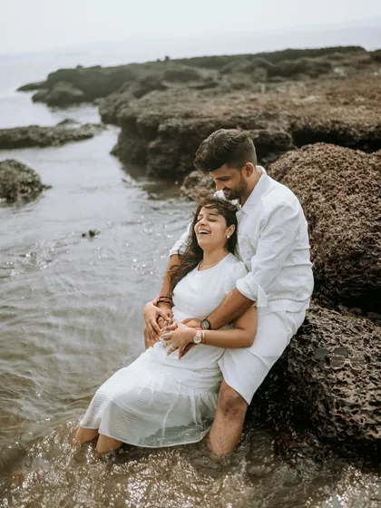A moment of pure laughter as a couple sits among the rocks with waves washing over them. These are the real, unscripted memories I love to capture.