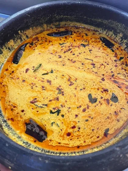 A close-up of the Rasakalan, with its vibrant colour and tempering of mustard seeds and dried red chilies. This dish perfectly captures the complex, layered flavours of Kerala cuisine.