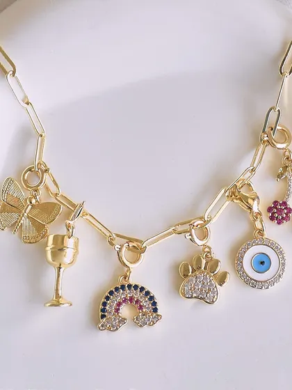 This charm necklace is a whole vibe, with a butterfly, a wine glass, a rainbow, a paw print, and an evil eye.