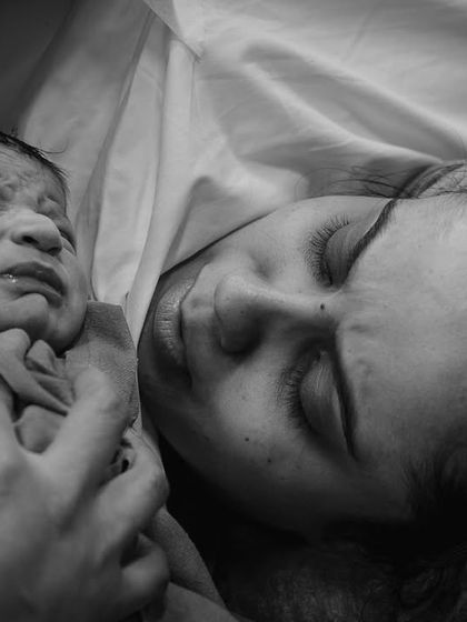An incredibly raw and intimate black and white moment between mother and child, just after birth, capturing the baby's first cries.