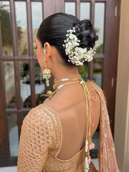 The back view of the bridesmaid's bun, adorned with a simple yet elegant spray of baby's breath.