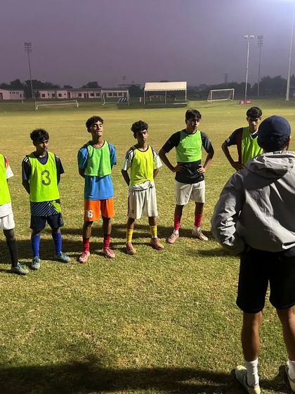 Under the floodlights, a coach briefs the team. Night sessions are a regular part of our intensive training schedule.