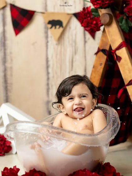 A fun milk bath with a red and black plaid camping theme, complete with a mini tent and floral decorations.