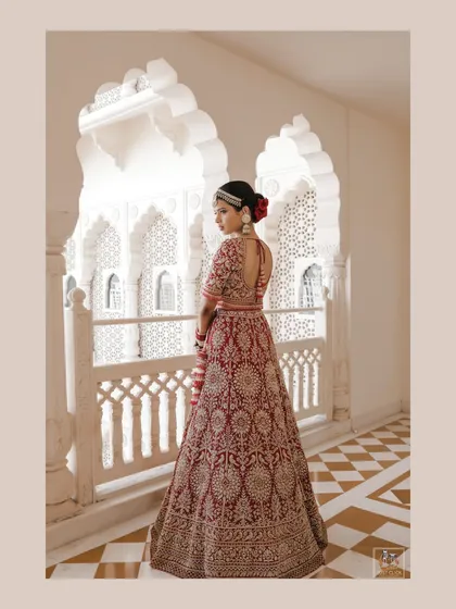 A full-length shot of the bride in her magnificent lehenga, framed by the beautiful arches of the Anantara palace in Jaipur.
