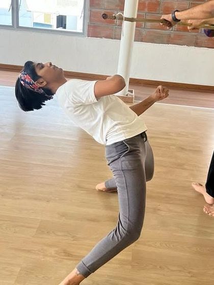 A student practices the esquiva, a fundamental defensive move, learning to dodge under a stick. This drill teaches agility and quick reflexes.