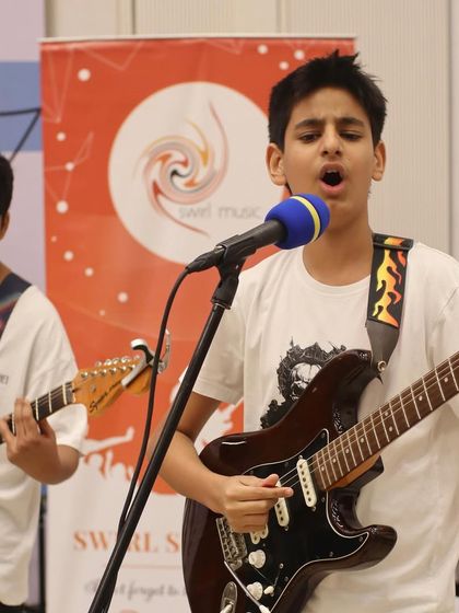 A student guitarist and vocalist leading his band at the Museum of Solutions (MuSo). Our stage performance training helps students learn to command the stage.