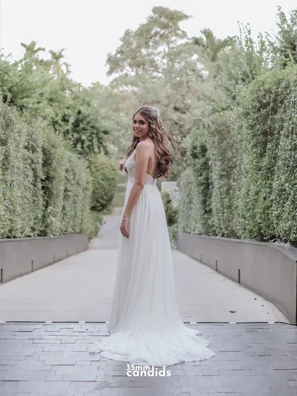 A full-length shot of Trisha in her flowing white gown, looking back with a smile. A beautiful and classic bridal portrait.