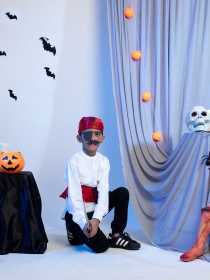 A young pirate model posing with his sword in a themed setting.