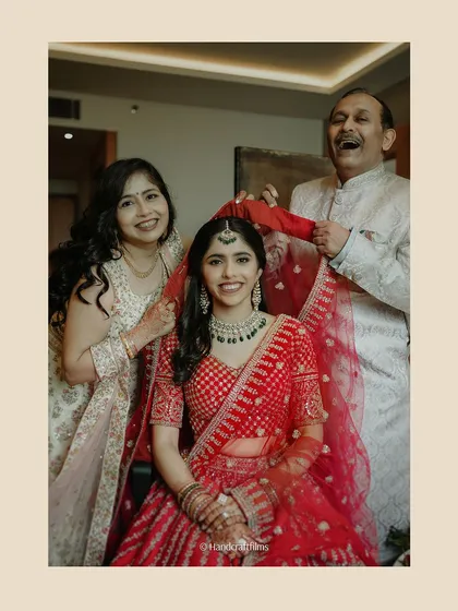 A precious family moment. The bride is getting her veil set by her parents, and their happy, emotional expressions are what weddings are all about.