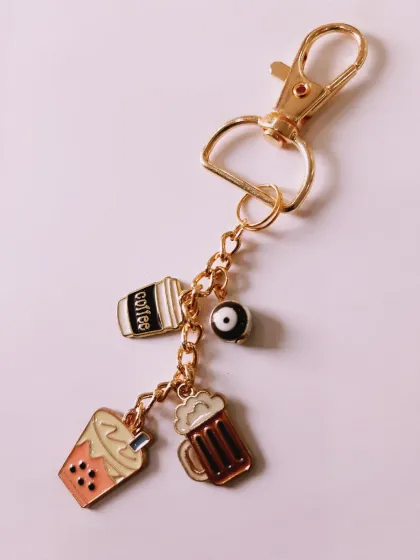 A close-up of the coffee, boba, beer, and evil eye charm keychain. It's a quirky and personalized accessory for your keys or bag.