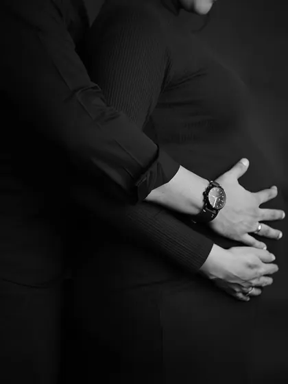 An artistic close-up in black and white, focusing on the hands embracing the baby bump.