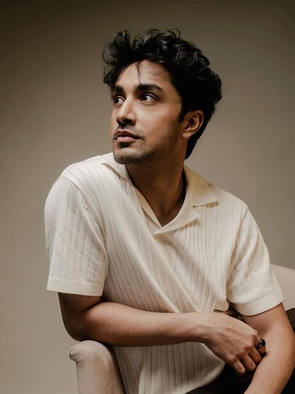 A relaxed portrait of Lakshya Parikh. The soft, off white knit shirt gives a comfortable and approachable feel to this studio shot.