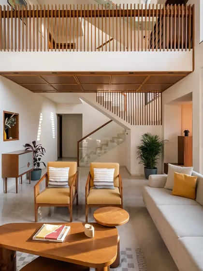 This view of the Amber House living area highlights our use of vertical lines and double-height volumes to create a sense of openness and connection. The wooden slat railings are a signature element, offering visual continuity between floors while allowing light to filter through the space.