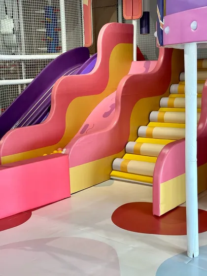A view of our colorful slides and pencil-themed stairs, designed to be as fun to look at as they are to play on.