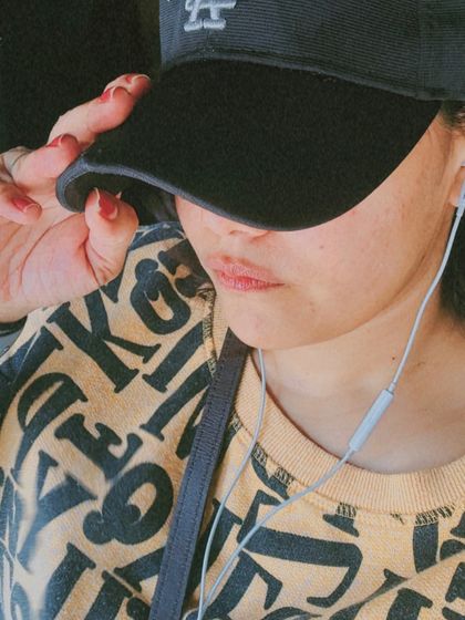 A close-up shot capturing a moment of simple living. The graphic sweatshirt and baseball cap create a low-key, comfortable look perfect for a relaxed Sunday.