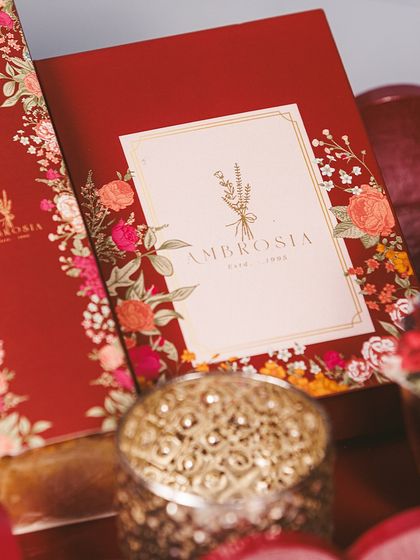 The packaging of our Imperial Diwali Hampers is as exquisite as the treats inside, featuring rich red and floral designs with gold foil accents.