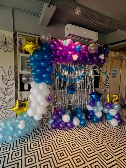 This L-shaped balloon arch in shades of blue, purple, and white is perfect for a teenager's birthday. I combined it with a silver tinsel curtain and star-shaped foil balloons to create a cool photo corner.